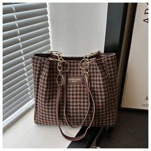 Détail du tissu à motif pied-de-poule et chaîne dorée sur un grand sac cabas