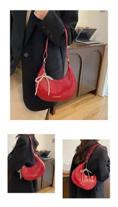Detail view of red hobo bag featuring pearl bow charm and Fashion print detail