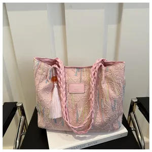 Detailed pink tote bag with quilted monogram texture, beaded handle and fringe charm