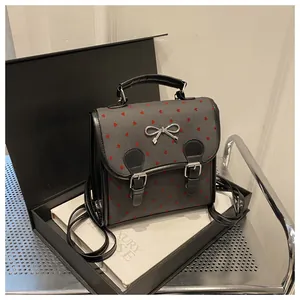 Detail of dark grey canvas backpack with red heart dots and silver bow decoration