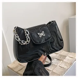 Detail of marble pattern shoulder bag with silver butterfly buckle and side chain