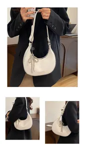 Detail of white half-moon shoulder bag with beaded bow charm and Fashion engraving