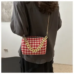 Détail du sac oreiller en tweed à carreaux rouge et blanc avec chaîne dorée