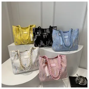 Detailed view of woven tote bags with colorful embroidery and elegant fringe tassels