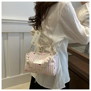 Detail of pink striped cylinder bag featuring pearl chain and cute panda print