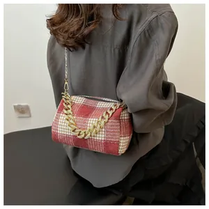 Détail du sac cylindre à motif pied-de-poule rouge et crème avec chaîne dorée