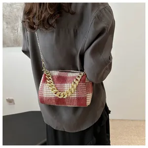 Détail du sac polochon à motif pied-de-poule rouge avec grosse chaîne dorée porté