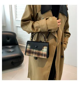 Vue latérale d'un petit sac à carreaux avec garniture en cuir noir sur un manteau kaki