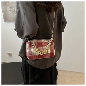 Détail du sac en tweed à carreaux rouge et blanc avec chaîne dorée et fine bandoulière