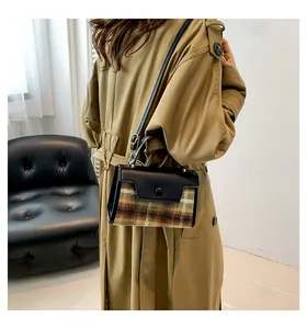 Détail du sac bandoulière à carreaux avec texture tweed vert et poignée en cuir noir