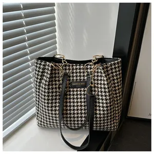 Détail du sac cabas pied-de-poule avec chaînes dorées et bandoulière noire élégante
