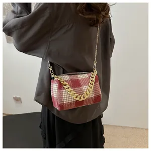 Détail d'un sac polochon à carreaux rouges et blancs avec chaîne dorée chic