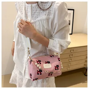 Detail of pink cylinder bag featuring textured fabric with cat prints and pearl chain