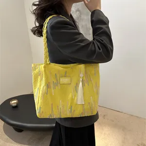 Yellow embossed tote bag with colorful zigzag stitching and woven shoulder strap