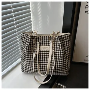 Détail du sac cabas à motif pied-de-poule avec bandoulière en cuir et chaîne dorée