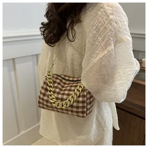 Détail du sac oreiller à carreaux avec poignée en chaîne dorée et texture en tweed