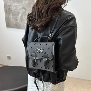 Mini gray backpack for women with black polka dots and silver bow detail in a stylish pose
