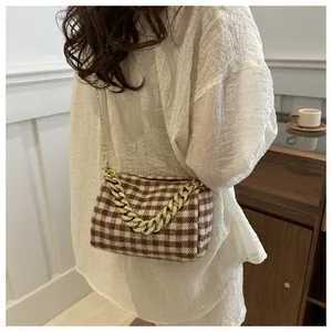 Vue détaillée du sac oreiller à carreaux marron avec une chaîne en métal doré tendance