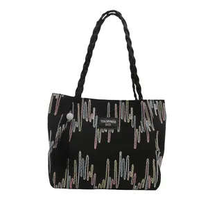 Black canvas tote bag with colorful wave embroidery and stylish tassel charm for women