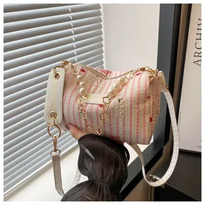Detailed view of striped pink cylinder bag with cherry prints and pearl chain handle