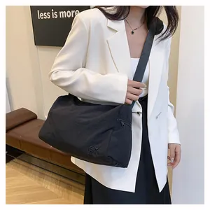 Sac bandoulière moderne en nylon noir avec large sangle porté sur une tenue blazer blanc