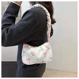 Détail du sac baguette blanc avec motifs de roses roses et bandoulière à volants