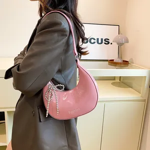 Pink crescent moon shoulder bag with beaded bow decoration and glossy finish