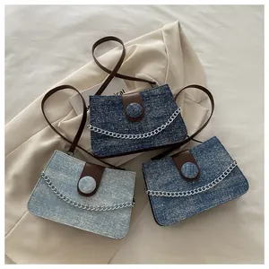 Detailopname van denim crossbodytassen met leren flap en zilveren decoratieve ketting