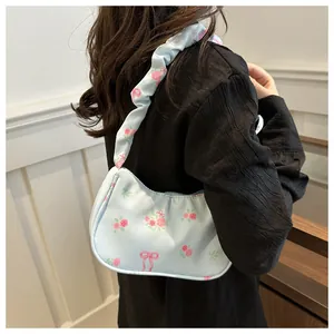 Detail van lichtblauwe hobo-tas met bloemenpatroon en een geplooide schouderband