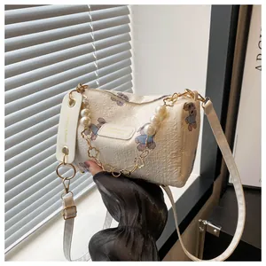 Detail of cream barrel bag featuring lavender bear print and pearl flower chain