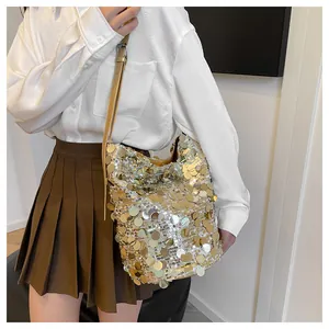 Dettaglio di una borsa a secchiello con paillettes oro e tracolla in pelle regolabile