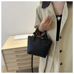 Dettaglio mini borsa a secchiello in pelle litchi nera con manico annodato