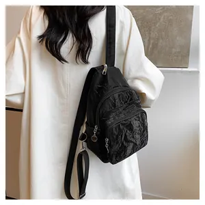 Close-up of black pleated nylon chest bag with multi-pocket design and adjustable strap