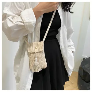 Détail d'un petit sac à bandoulière en paille tressée beige avec franges et fermoir doré