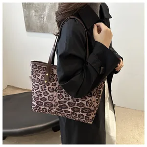 Detail view of leopard print tote bag with brown leather handles and gold studs