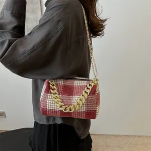 Sac oreiller à carreaux rouges et blancs avec chaîne dorée porté par un mannequin