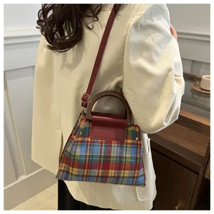 Detail of vintage plaid bag with wooden handles and leather strap on a corduroy jacket