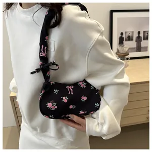Détail du sac croissant noir avec imprimé floral rose et bandoulière à nœud élégant