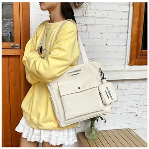 Outdoor-Aufnahme einer beigen Canvas-Tasche mit kleinem Beutel an einem Modell