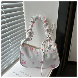 Détail du sac sous le bras blanc avec imprimé rose, poignée froncée et ruban à nœud