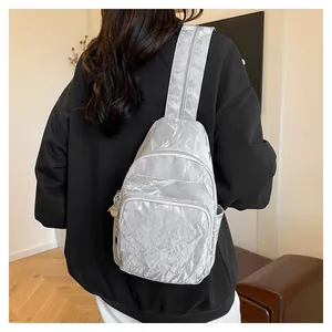 Detail of silver metallic pleated chest bag with textured nylon and zipper compartments