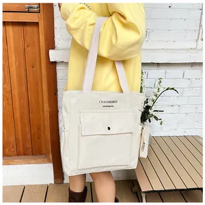 Tragebild der cremeweißen Canvas-Tasche mit Fronttasche und kleinem Geldbeutel