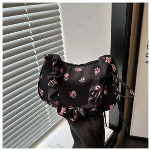 Gros plan du sac floral noir avec motifs de roses et poignée à texture froissée