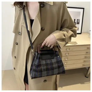 Detailed macro view of retro plaid wool handbag with brown circular handle and black leather flap