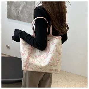 Detail of white tote bag with pink graffiti prints and handle worn by model