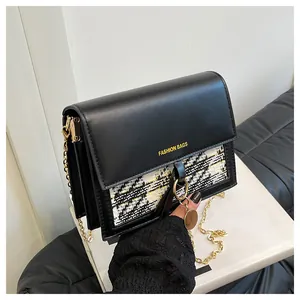 Detailed view of black tweed crossbody bag with gold chain and circular pendant