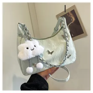 Detail of light green pleated shoulder bag with butterfly charm and fluffy cloud pendant