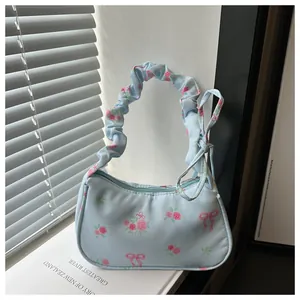 Détail d'un sac à main bleu clair avec motifs de roses et poignée à effet froncé