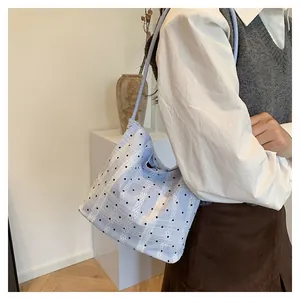 Close-up of light blue lace bucket bag with black polka dots and vertical lines on model