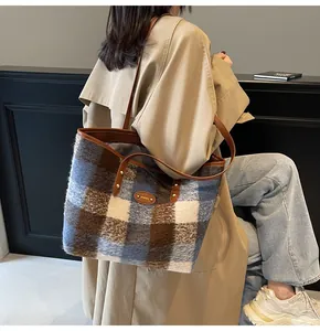 Détail du cabas en laine à carreaux avec anses en cuir porté à l'épaule pour le bureau